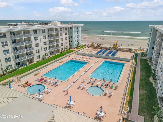 view of swimming pool with a view of the beach, a water view, and a patio area