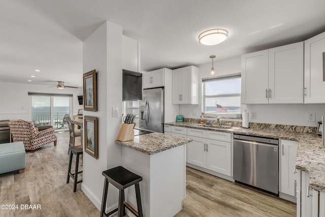 kitchen with a kitchen breakfast bar, white cabinetry, a healthy amount of sunlight, and appliances with stainless steel finishes