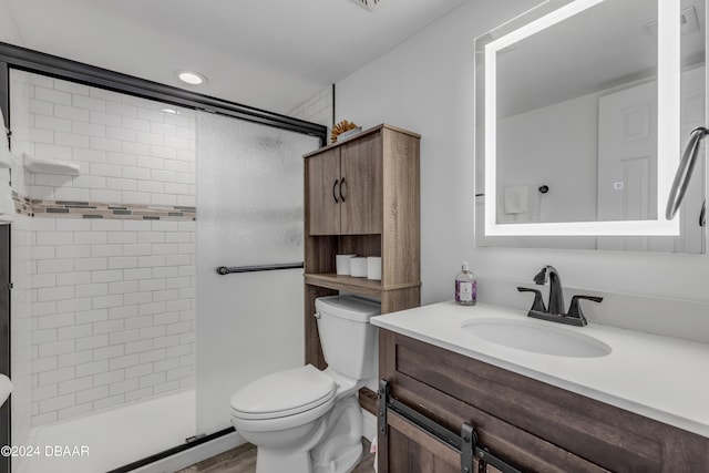 bathroom with toilet, vanity, hardwood / wood-style flooring, and a shower with door