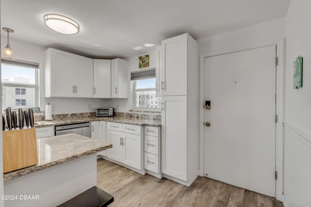 kitchen featuring light wood-type flooring, decorative light fixtures, light stone counters, and white cabinets