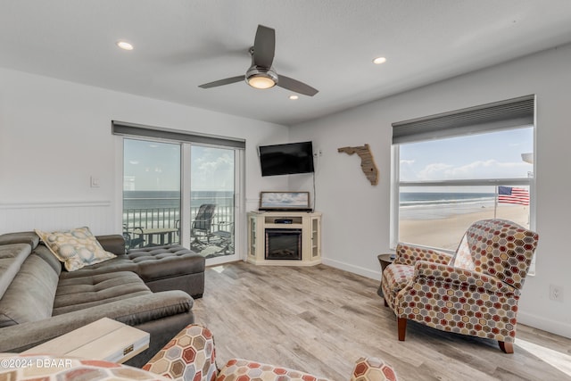 living room with a fireplace, ceiling fan, and light wood-type flooring