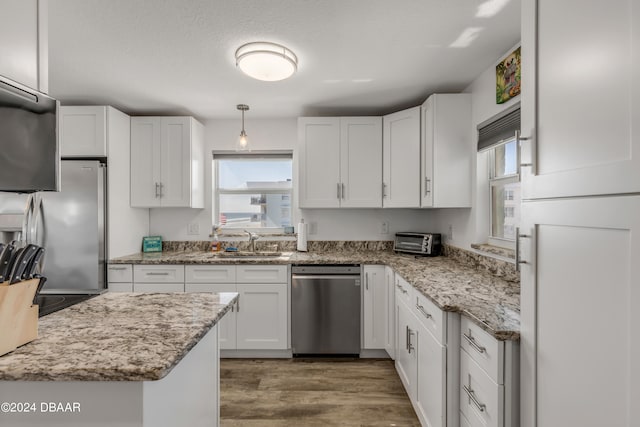 kitchen featuring white cabinetry, stainless steel appliances, a healthy amount of sunlight, and pendant lighting