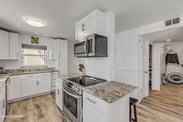 kitchen with a kitchen island, light wood-type flooring, white cabinets, and stainless steel appliances