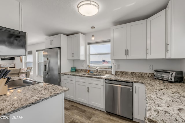 kitchen featuring stainless steel appliances, white cabinetry, pendant lighting, sink, and light hardwood / wood-style flooring