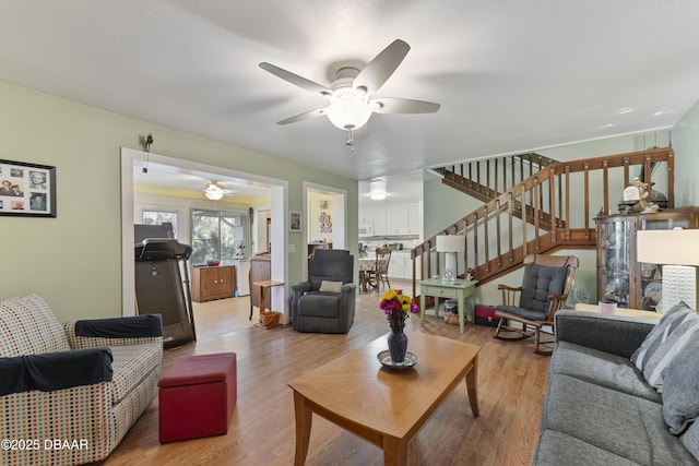 living room featuring stairway, wood finished floors, and a ceiling fan