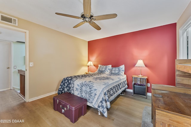 bedroom with a ceiling fan, wood finished floors, visible vents, and baseboards