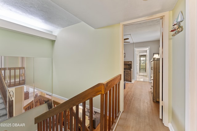 hall with an upstairs landing, light wood-style floors, and a textured ceiling