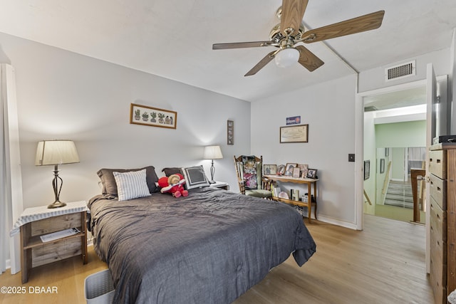 bedroom featuring light wood-type flooring, visible vents, baseboards, and ceiling fan