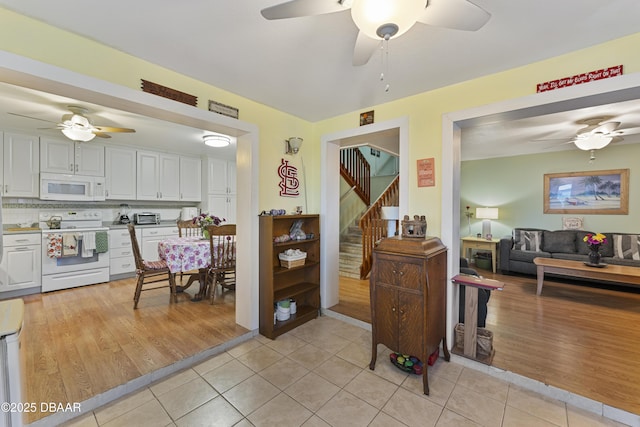 kitchen featuring white appliances, white cabinets, light tile patterned floors, and tasteful backsplash