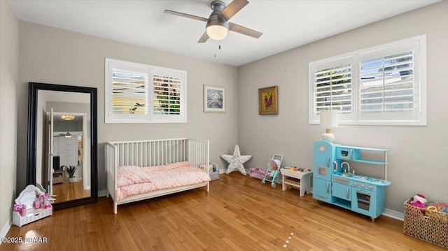 bedroom with light wood-style flooring, baseboards, and ceiling fan