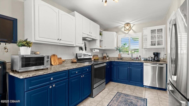 kitchen with tasteful backsplash, a toaster, stainless steel appliances, blue cabinetry, and a sink