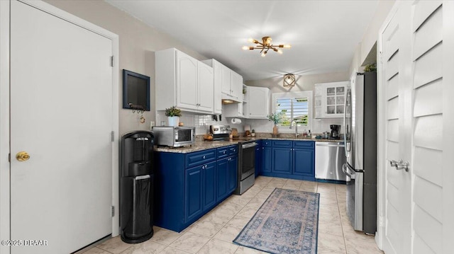 kitchen with blue cabinetry, decorative backsplash, appliances with stainless steel finishes, white cabinetry, and a sink