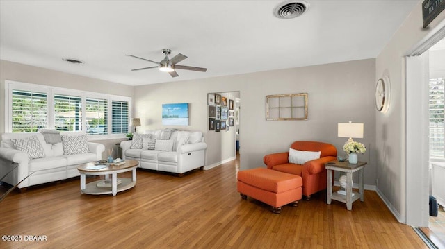 living area featuring light wood-type flooring, visible vents, ceiling fan, and baseboards