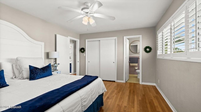 bedroom with a closet, ensuite bathroom, light wood-style floors, a ceiling fan, and baseboards