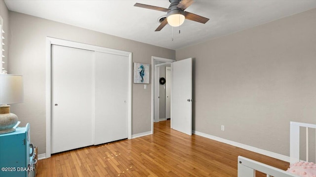 unfurnished bedroom featuring a closet, wood-type flooring, a ceiling fan, and baseboards