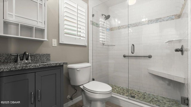 full bath with toilet, a stall shower, baseboards, and vanity