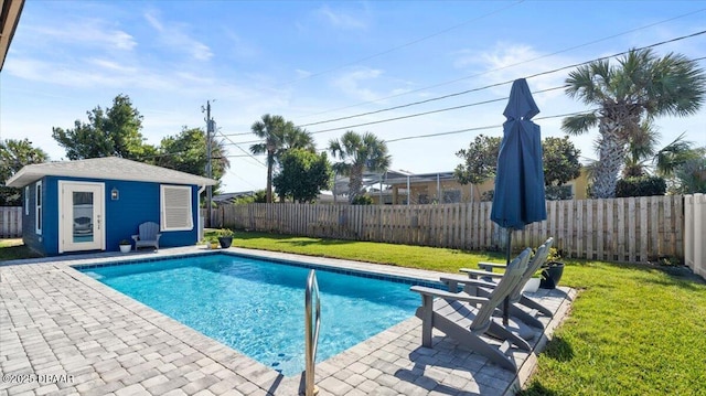 view of pool featuring an outbuilding, a fenced backyard, a patio, and a lawn