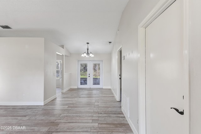 entrance foyer with french doors, visible vents, light wood-style floors, a chandelier, and baseboards