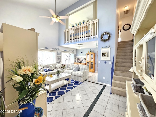 living room featuring ceiling fan, light tile patterned floors, and a high ceiling