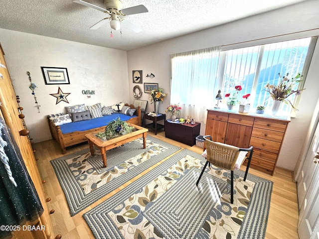 living room featuring ceiling fan, a textured ceiling, and light hardwood / wood-style floors