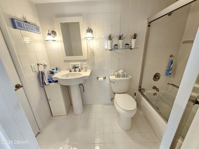 bathroom featuring toilet, tile walls, shower / bath combination with glass door, and tile patterned flooring