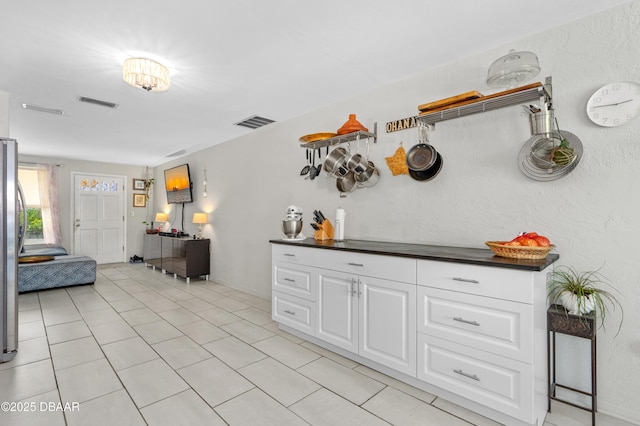 kitchen with white cabinetry, light tile patterned floors, and stainless steel refrigerator