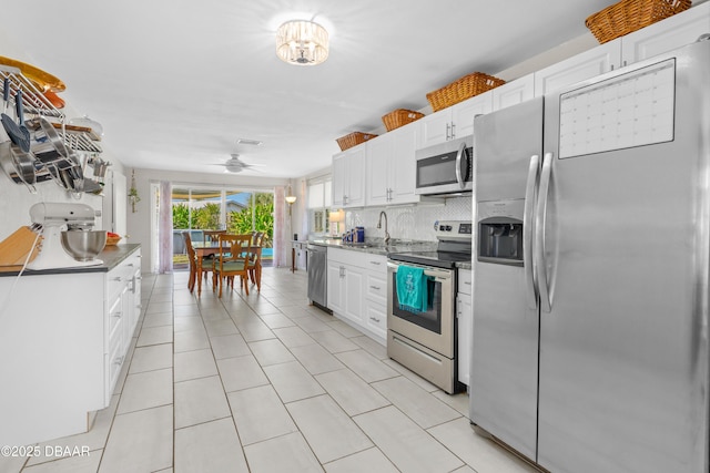 kitchen with sink, white cabinetry, light tile patterned floors, appliances with stainless steel finishes, and decorative backsplash