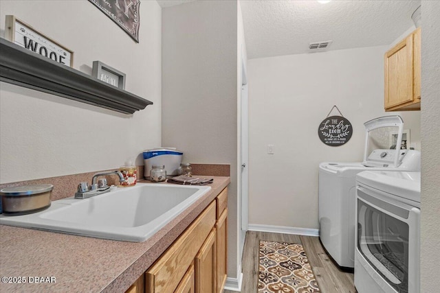 21 Whittingham Ln, Palm Coast, FL 32164 - washroom with a sink, light wood-type flooring, cabinet space, washing machine and dryer, and visible vents