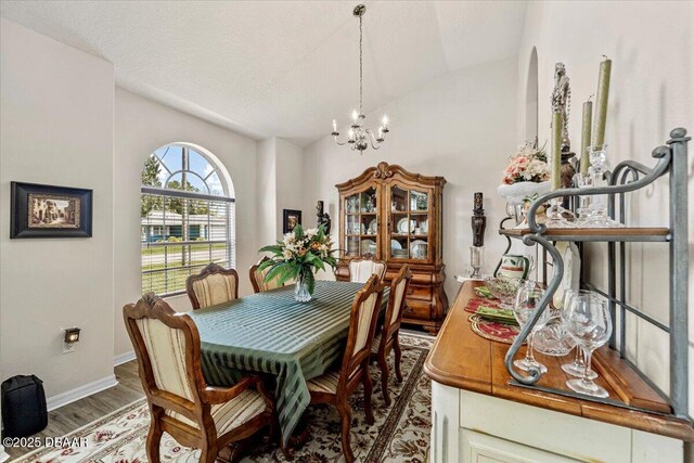 21 Whittingham Ln, Palm Coast, FL 32164 - dining space with wood finished floors, vaulted ceiling, baseboards, and an inviting chandelier