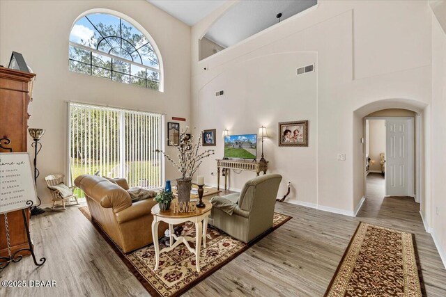 21 Whittingham Ln, Palm Coast, FL 32164 - living area featuring arched walkways, a high ceiling, visible vents, and light wood-type flooring