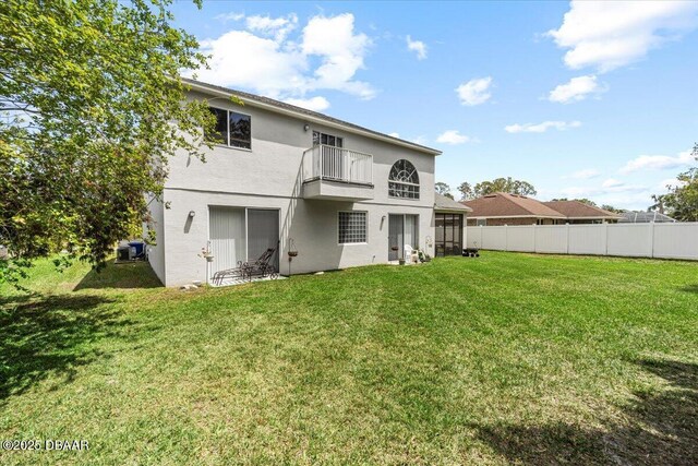 21 Whittingham Ln, Palm Coast, FL 32164 - rear view of house featuring fence, a lawn, a balcony, and stucco siding