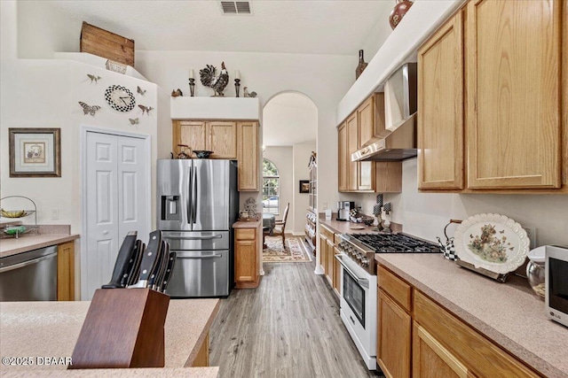 21 Whittingham Ln, Palm Coast, FL 32164 - kitchen featuring arched walkways, visible vents, light wood-style floors, wall chimney range hood, and appliances with stainless steel finishes