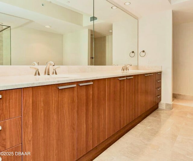 bathroom with double vanity, a sink, visible vents, and baseboards