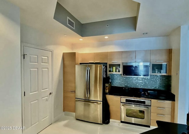 kitchen featuring visible vents, appliances with stainless steel finishes, decorative backsplash, dark countertops, and a raised ceiling