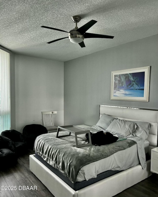 bedroom with a ceiling fan, a textured ceiling, and wood finished floors