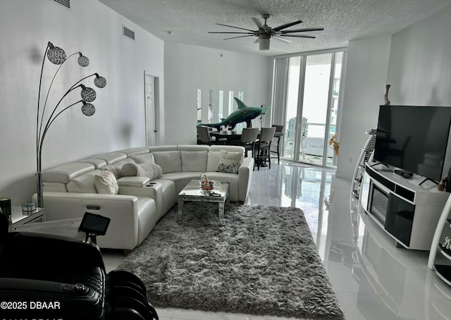 living room with a textured ceiling, visible vents, a ceiling fan, marble finish floor, and expansive windows