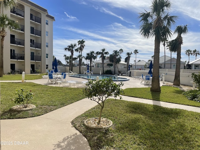 view of community featuring a swimming pool, a lawn, and a patio area