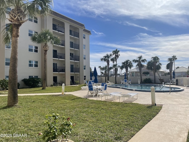 view of community featuring a pool, a patio area, and a lawn