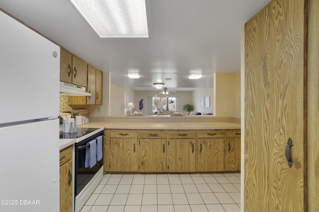 kitchen featuring under cabinet range hood, light countertops, range with electric stovetop, freestanding refrigerator, and light tile patterned flooring