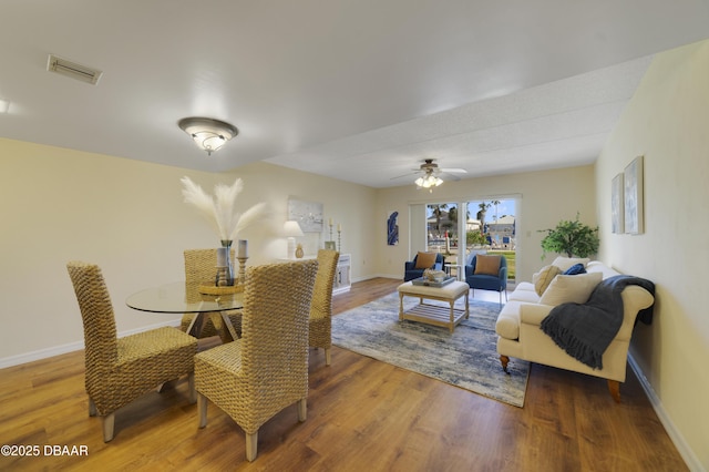 dining space with a ceiling fan, wood finished floors, visible vents, and baseboards