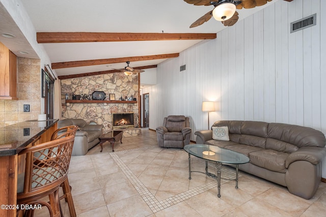 living room with lofted ceiling with beams and a stone fireplace