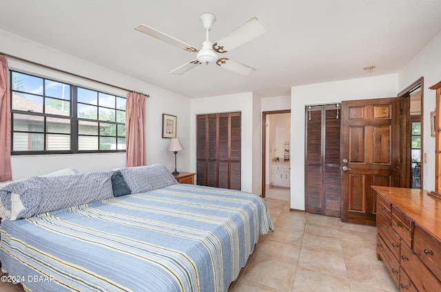 bedroom with ceiling fan, light tile patterned flooring, ensuite bathroom, and multiple closets