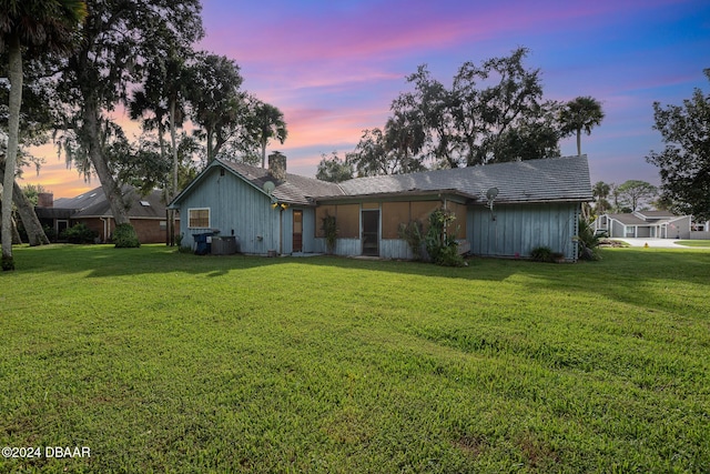 back house at dusk featuring a yard