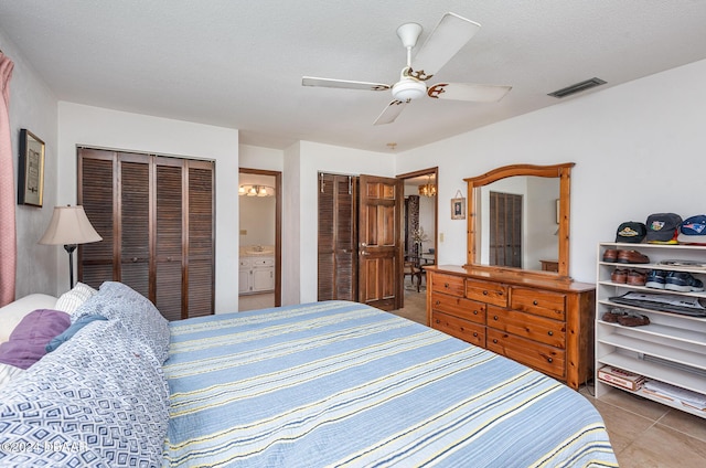 tiled bedroom featuring connected bathroom, ceiling fan, and a textured ceiling