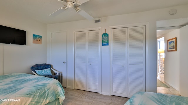 tiled bedroom featuring multiple closets and ceiling fan