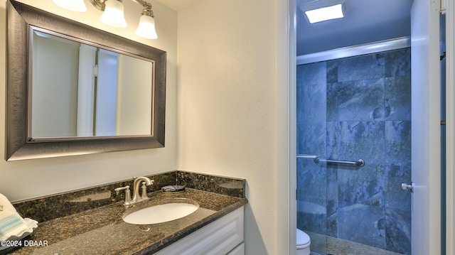 bathroom featuring toilet, a shower, and vanity