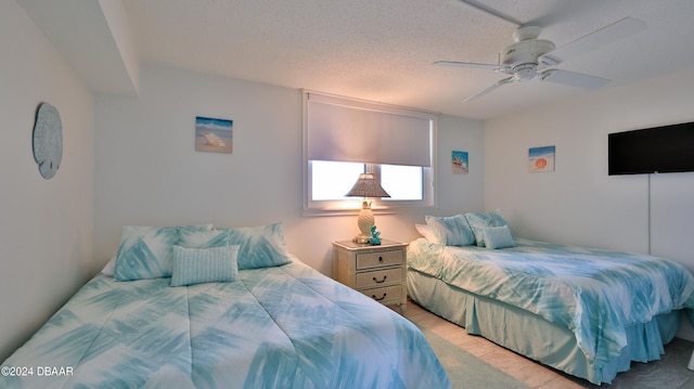 bedroom with light hardwood / wood-style floors, a textured ceiling, and ceiling fan