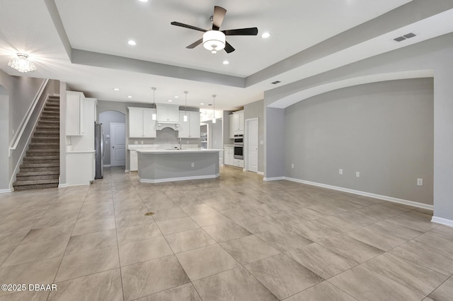 unfurnished living room featuring light tile patterned floors, a tray ceiling, and ceiling fan