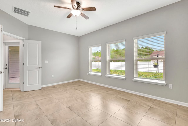 empty room featuring ceiling fan, plenty of natural light, and light tile patterned flooring