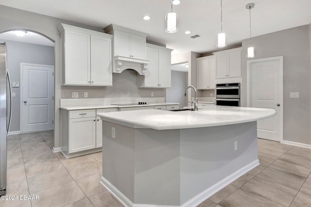 kitchen featuring sink, white cabinetry, a kitchen island with sink, and hanging light fixtures